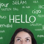 Mulher na frente de um quadro com palavras em diversas línguas