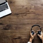 Mão segurando o fone e um notebook a frente