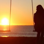 Mulher em um balanço olhando para o balanço do lado vazio