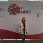 Cristina Gonzales em frente o painel do 12º congresso ABRATES