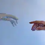 fundo azul com uma mão de robo no lado esquerdo e no outro lado uma mão humana