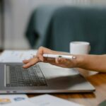 Pessoa mexendo no notebook com uma caneta na mão